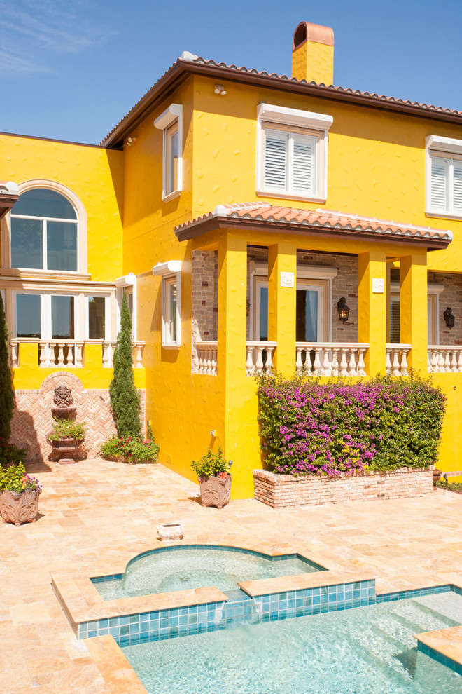 Foto de fachada amarilla mediterránea extra grande de tres plantas con revestimiento de estuco