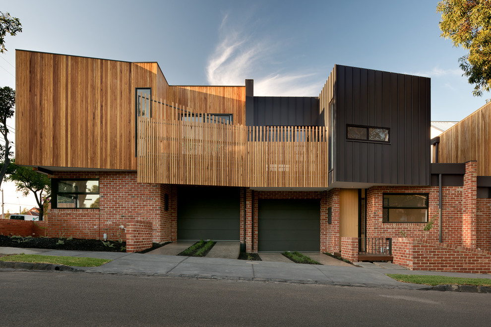 This is an example of a medium sized and red contemporary two floor brick house exterior in Melbourne with a flat roof.