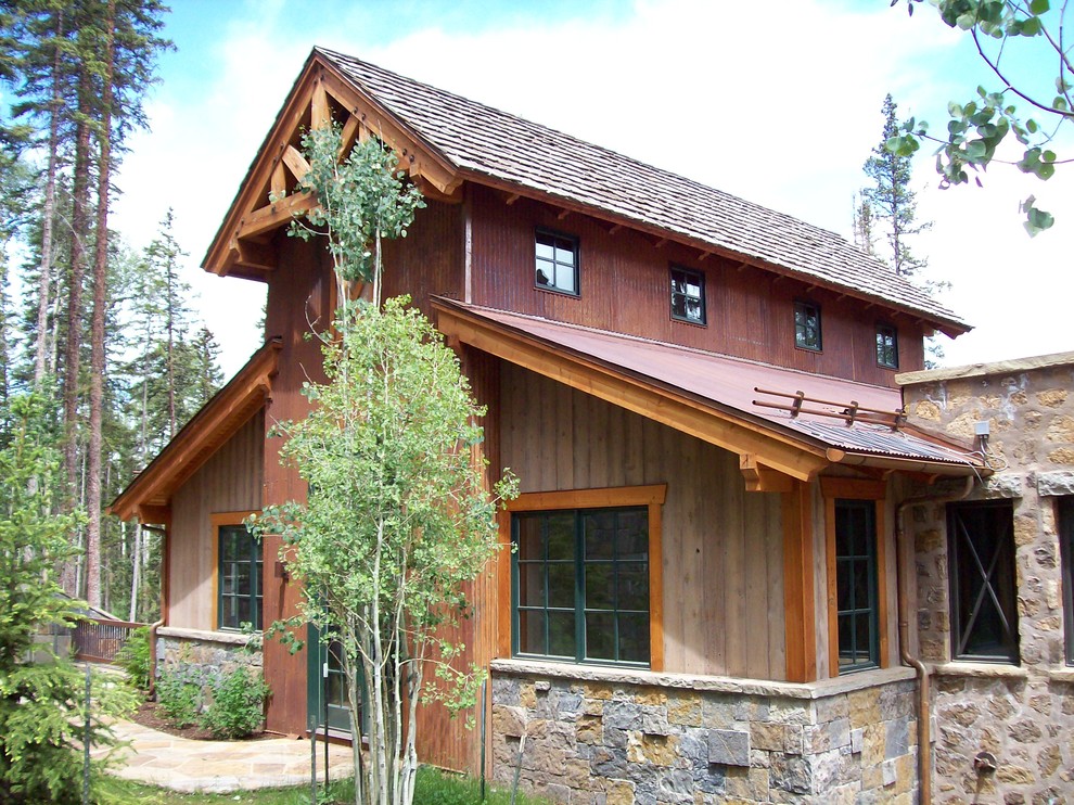 Foto della facciata di una casa marrone rustica a tre piani con rivestimento in legno e tetto a capanna
