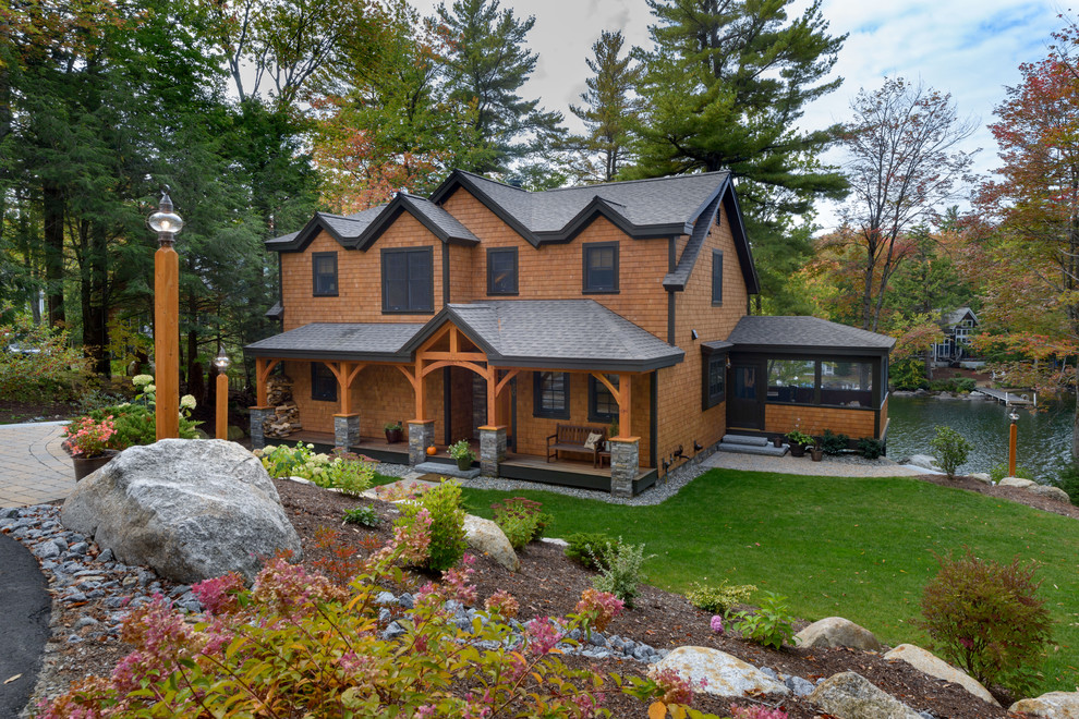 На фото: большой, двухэтажный, деревянный, коричневый частный загородный дом в стиле рустика с двускатной крышей и крышей из гибкой черепицы
