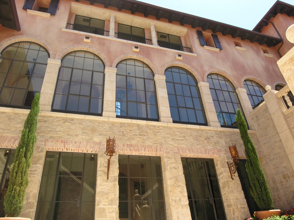 Diseño de fachada marrón mediterránea grande de tres plantas con revestimientos combinados