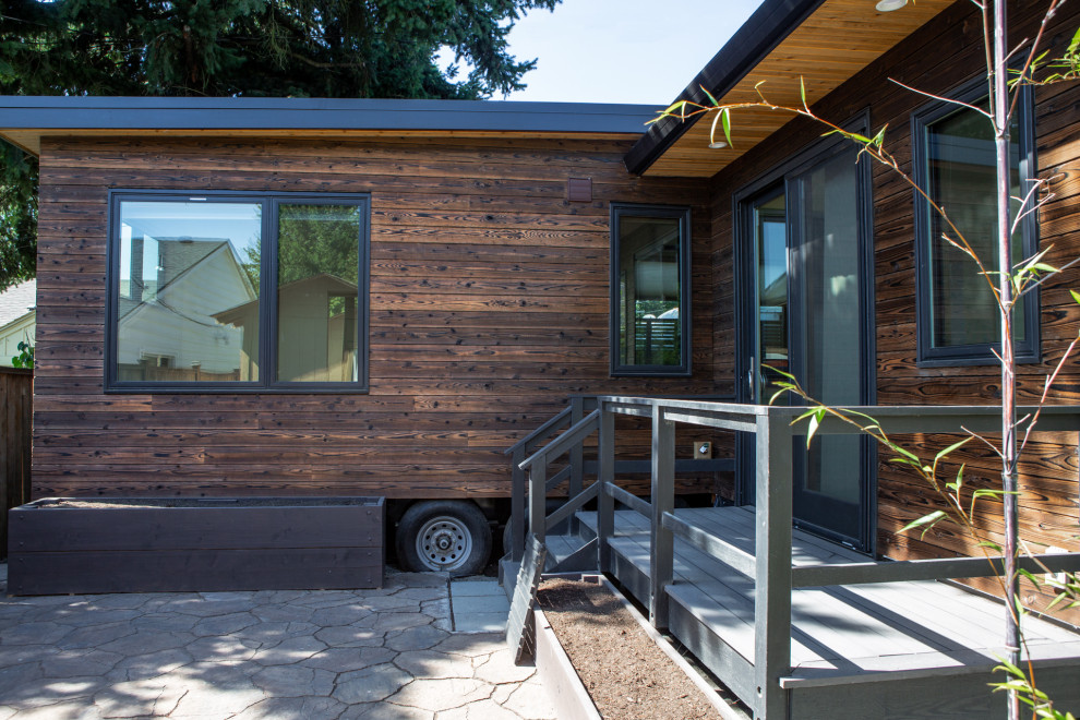 Идея дизайна: маленький, одноэтажный, деревянный, коричневый многоквартирный дом в стиле модернизм с плоской крышей и металлической крышей для на участке и в саду