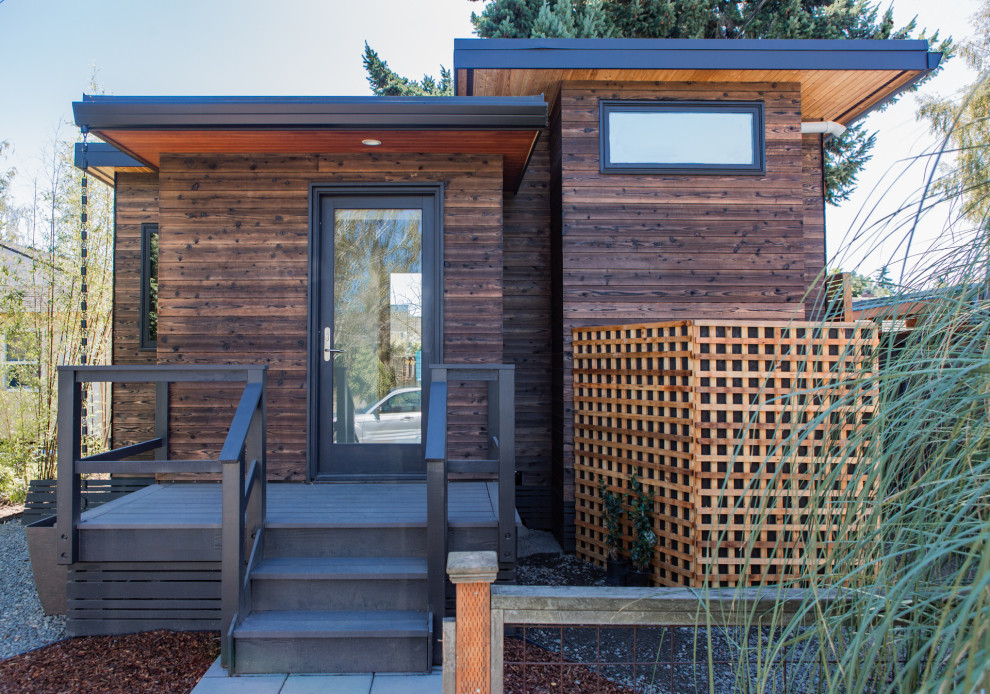 На фото: маленький, одноэтажный, деревянный, коричневый многоквартирный дом в стиле модернизм с плоской крышей и металлической крышей для на участке и в саду с
