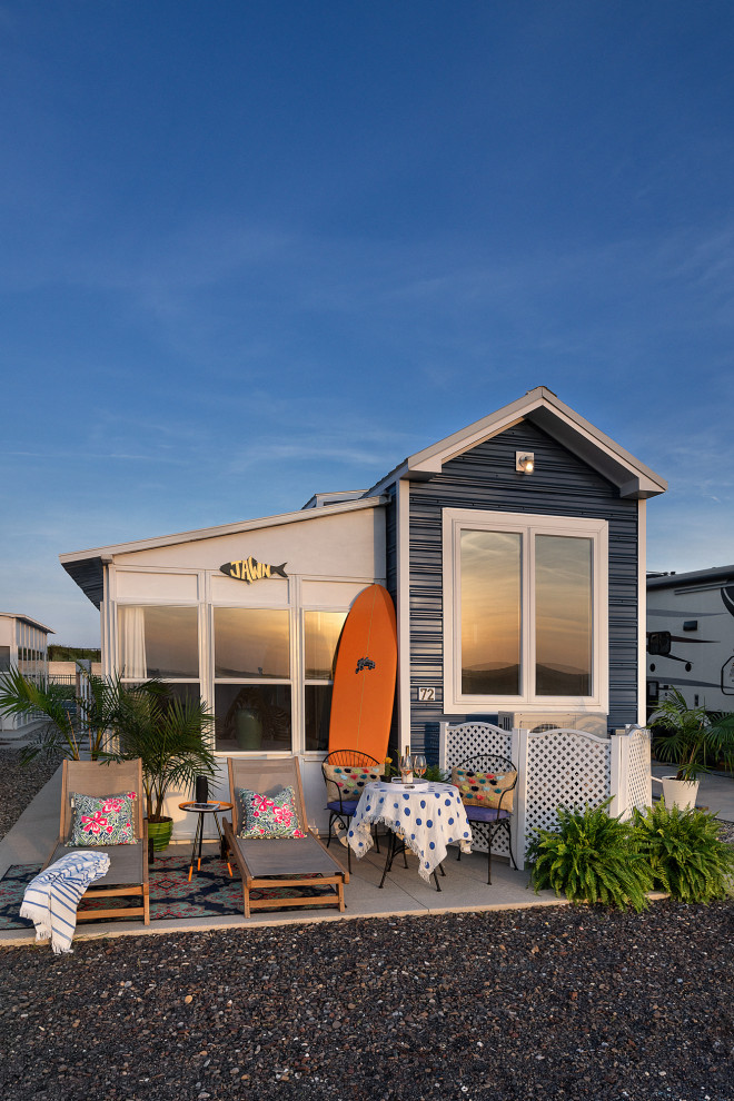 Пример оригинального дизайна: маленький, двухэтажный, синий мини дом в морском стиле с облицовкой из металла, вальмовой крышей и металлической крышей для на участке и в саду