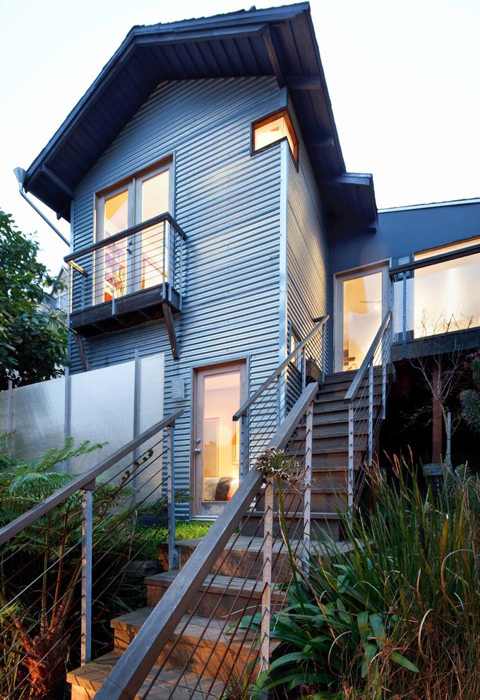Свежая идея для дизайна: маленький, двухэтажный, серый многоквартирный дом в стиле лофт с облицовкой из металла и двускатной крышей для на участке и в саду - отличное фото интерьера