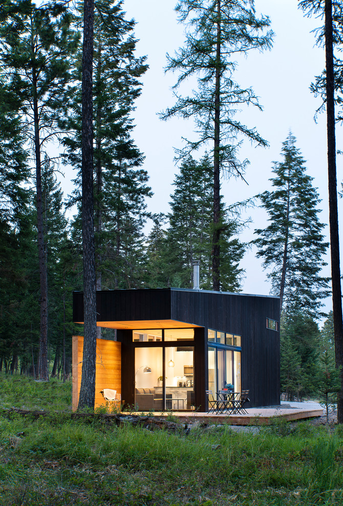 Cette image montre une façade de Tiny House noire chalet de plain-pied avec un toit plat.