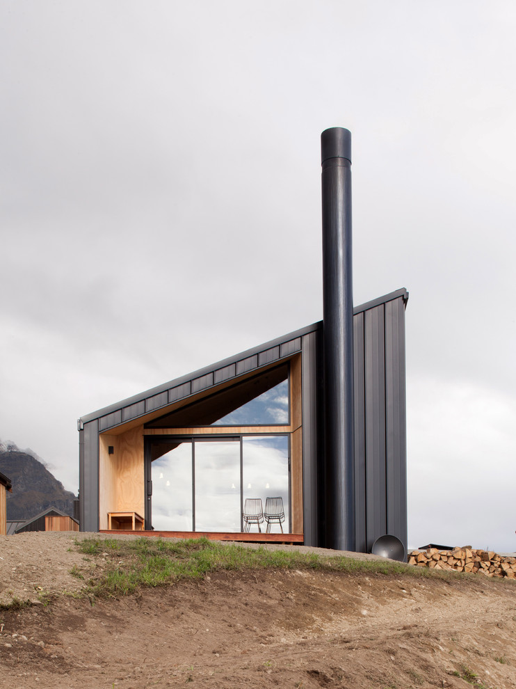 Diseño de fachada negra actual pequeña de dos plantas con revestimiento de metal y tejado a dos aguas
