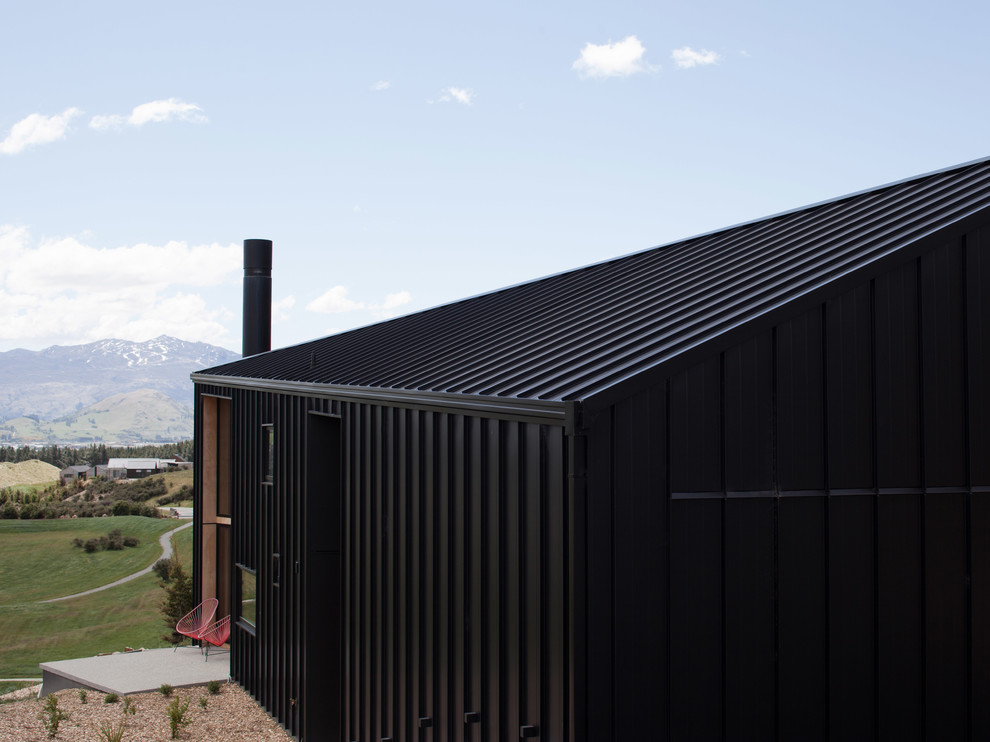 Imagen de fachada negra contemporánea pequeña de dos plantas con revestimiento de metal y tejado a dos aguas