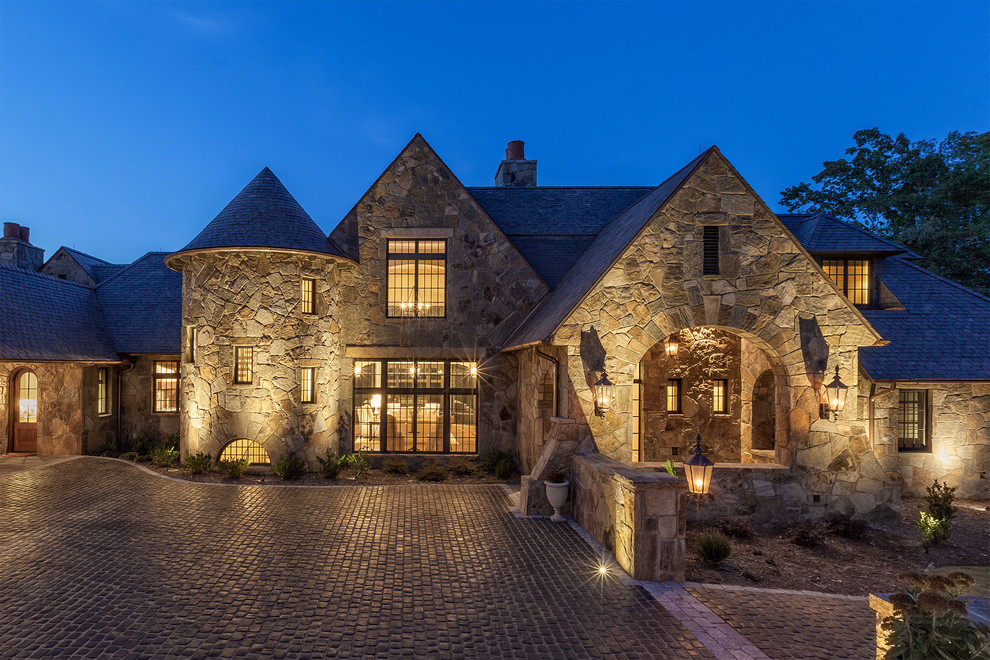 Стильный дизайн: огромный, двухэтажный, коричневый дом в стиле рустика с облицовкой из камня и двускатной крышей - последний тренд