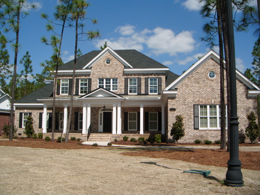 Cette photo montre une grande façade de maison marron chic en brique à un étage avec un toit à deux pans et un toit en shingle.