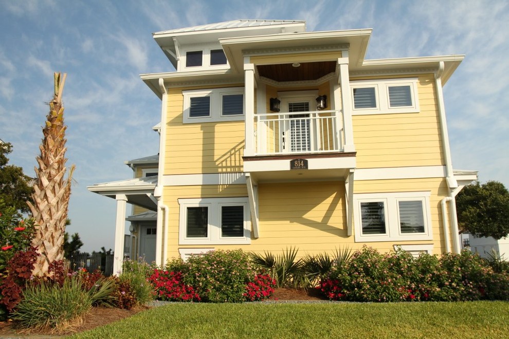 Exempel på ett maritimt gult hus, med tre eller fler plan och fiberplattor i betong