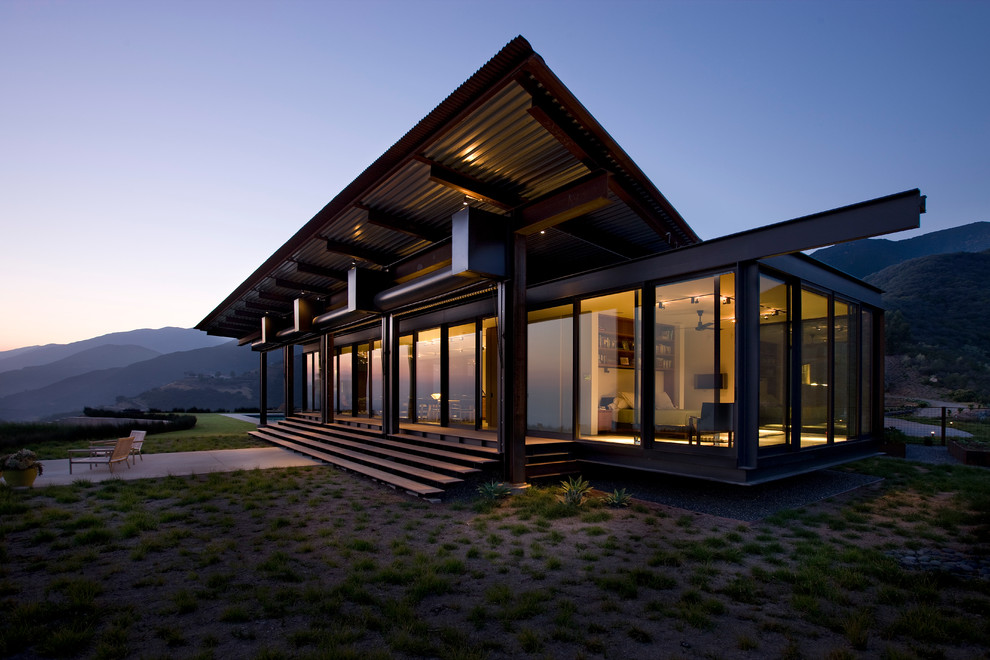 Imagen de fachada de casa minimalista grande de una planta con revestimiento de vidrio, tejado plano y tejado de metal