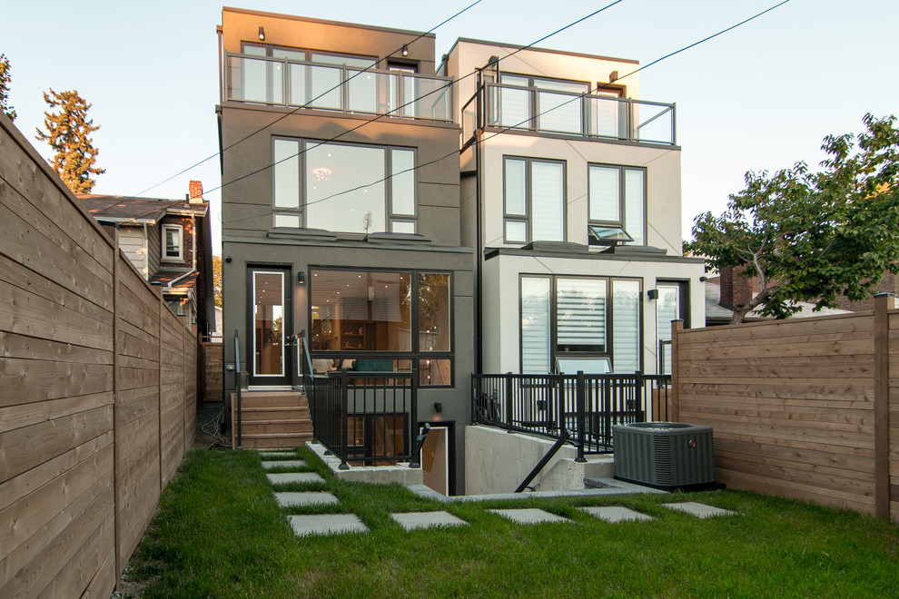 Mittelgroßes, Dreistöckiges Modernes Reihenhaus mit Putzfassade, grauer Fassadenfarbe und Flachdach in Toronto
