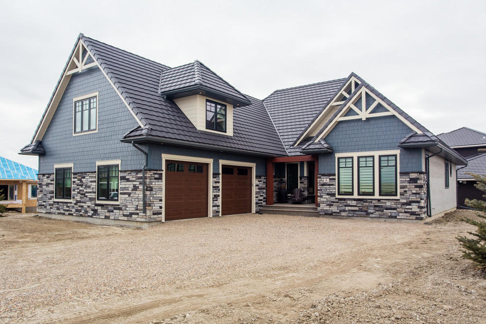Large and blue traditional split-level house exterior in Calgary with mixed cladding and a pitched roof.