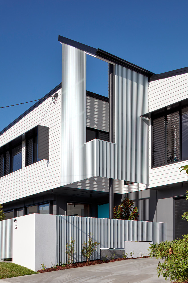 Example of a mid-sized trendy white two-story house exterior design in Brisbane with a metal roof