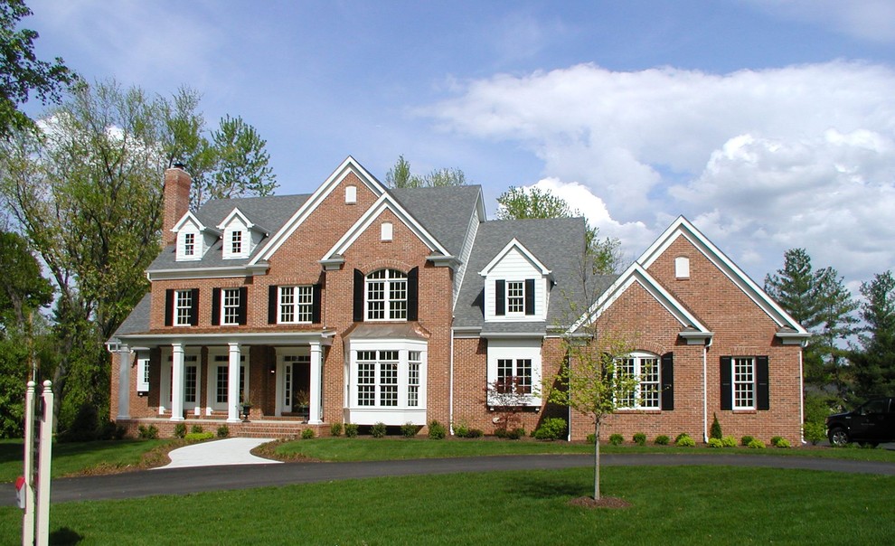 Пример оригинального дизайна: большой, двухэтажный, кирпичный дом в классическом стиле с двускатной крышей