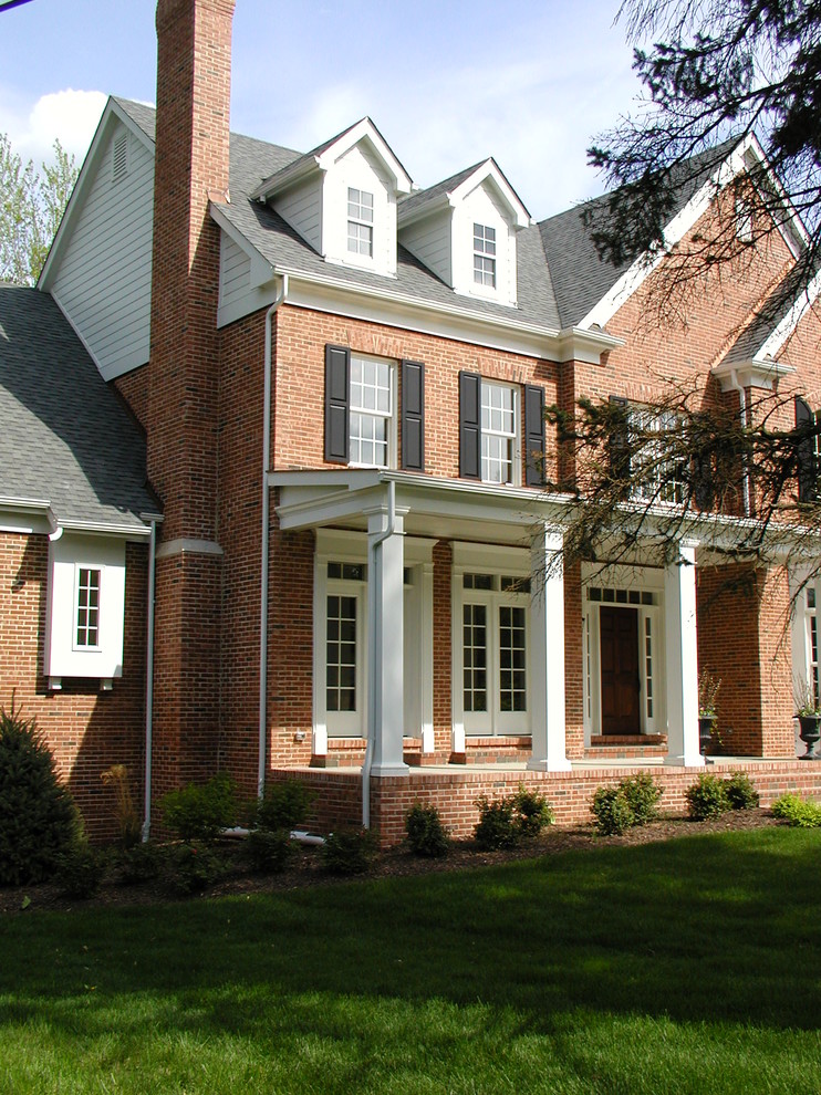 Immagine della facciata di una casa grande classica a due piani con rivestimento in mattoni e tetto a capanna