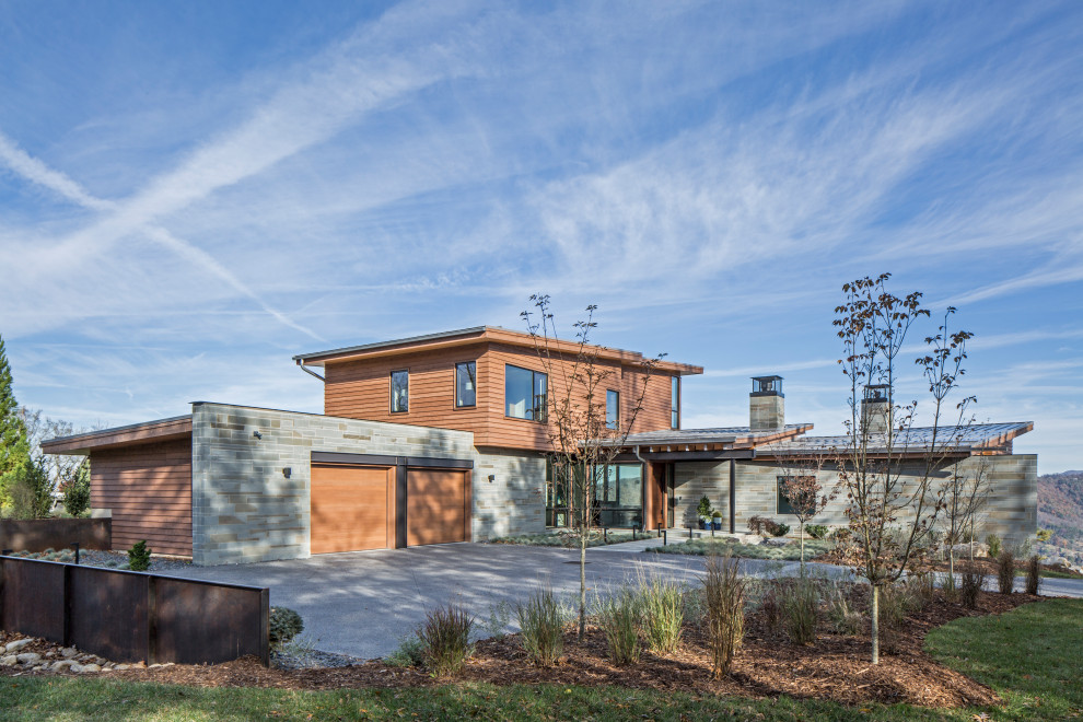 Cette image montre une grande façade de maison multicolore design à un étage avec un revêtement mixte et un toit en appentis.