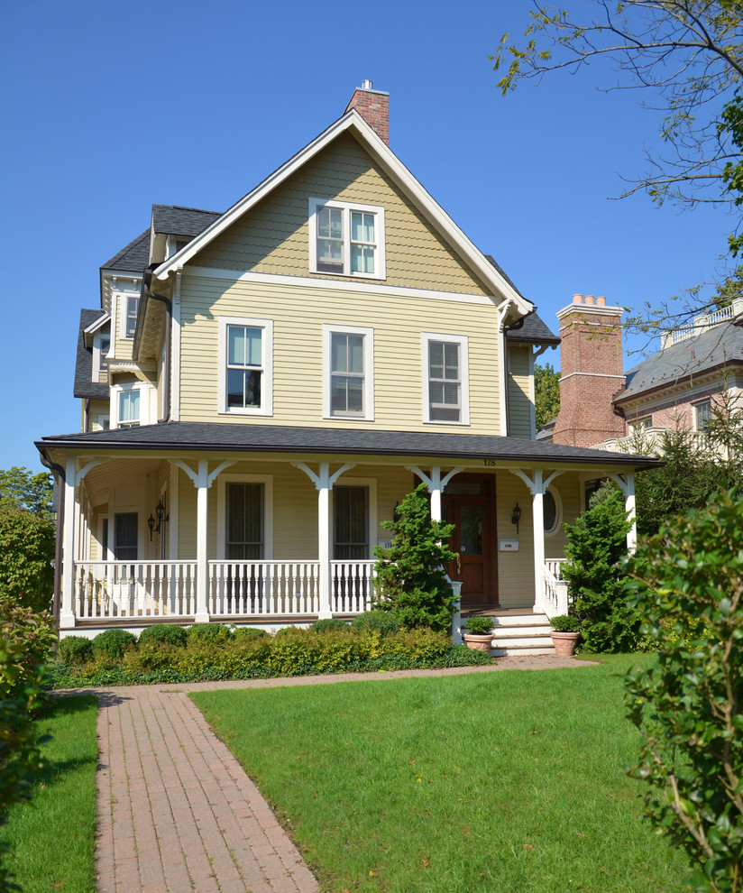 Immagine della villa beige vittoriana a tre piani con rivestimento in legno