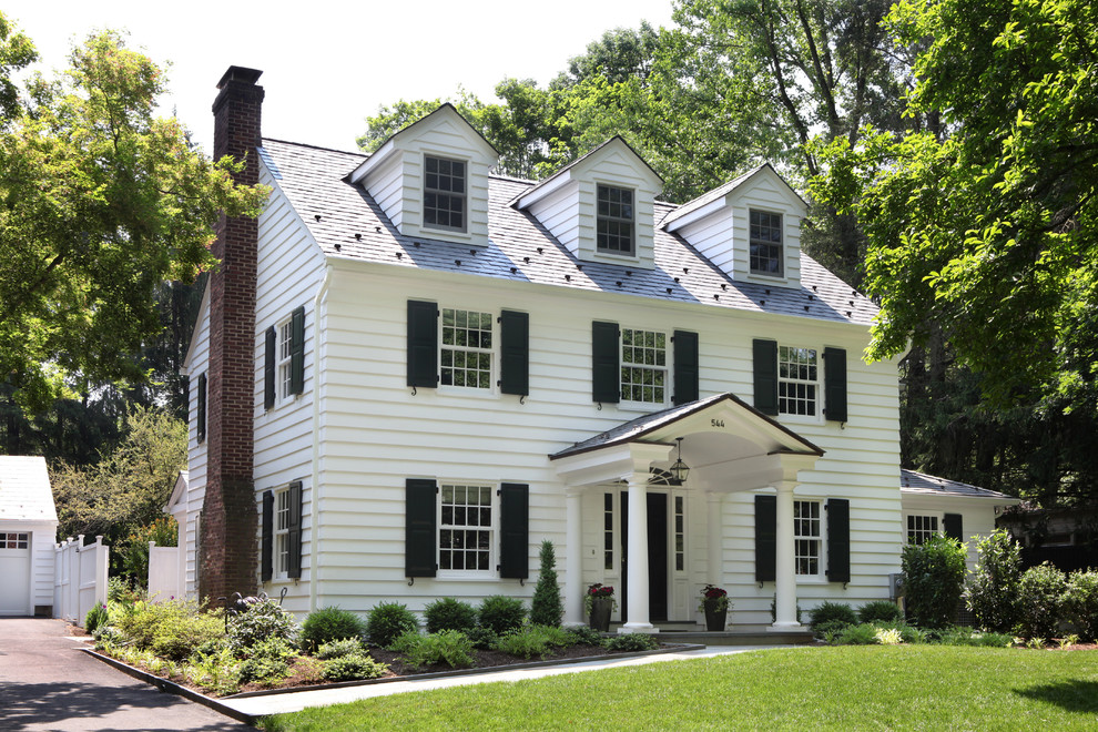 Diseño de fachada de casa blanca clásica grande de tres plantas con revestimiento de madera, tejado a dos aguas y tejado de teja de barro