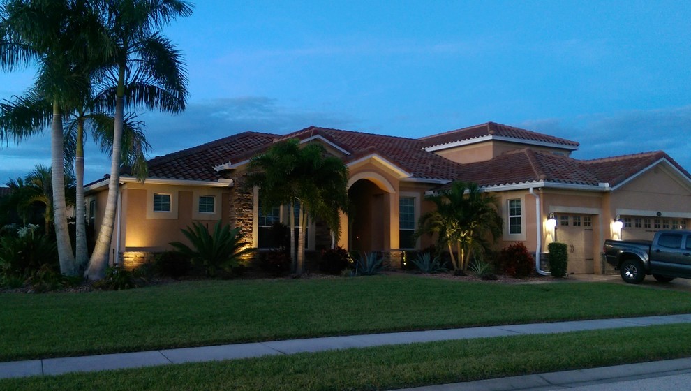 Photo of a medium sized and beige world-inspired bungalow render house exterior in Orlando with a pitched roof.