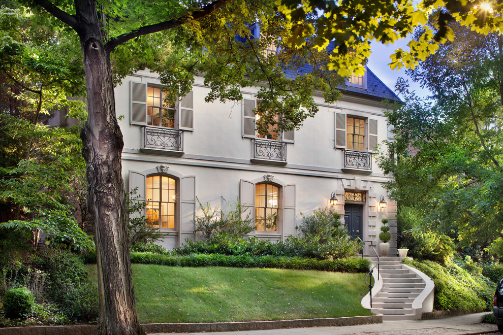 Large elegant brown three-story stucco exterior home photo in DC Metro with a hip roof