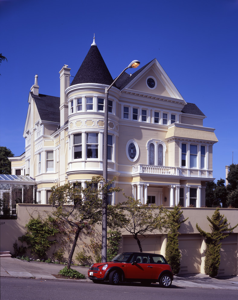 Immagine della facciata di una casa grande vittoriana a tre piani con rivestimento in legno, tetto a capanna e abbinamento di colori