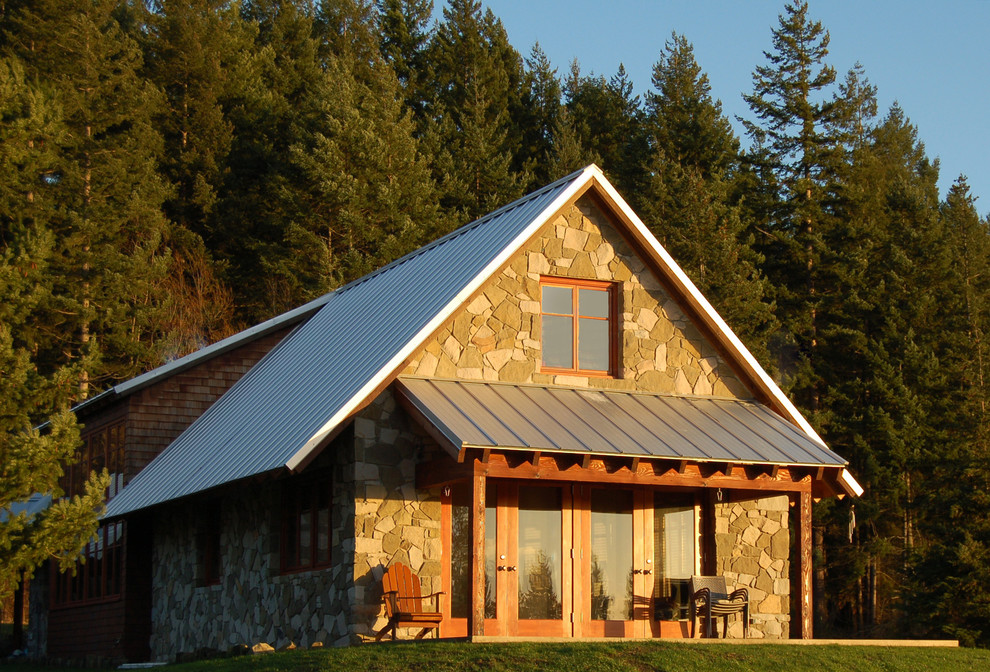 Esempio della facciata di una casa classica con rivestimento in pietra e tetto a capanna