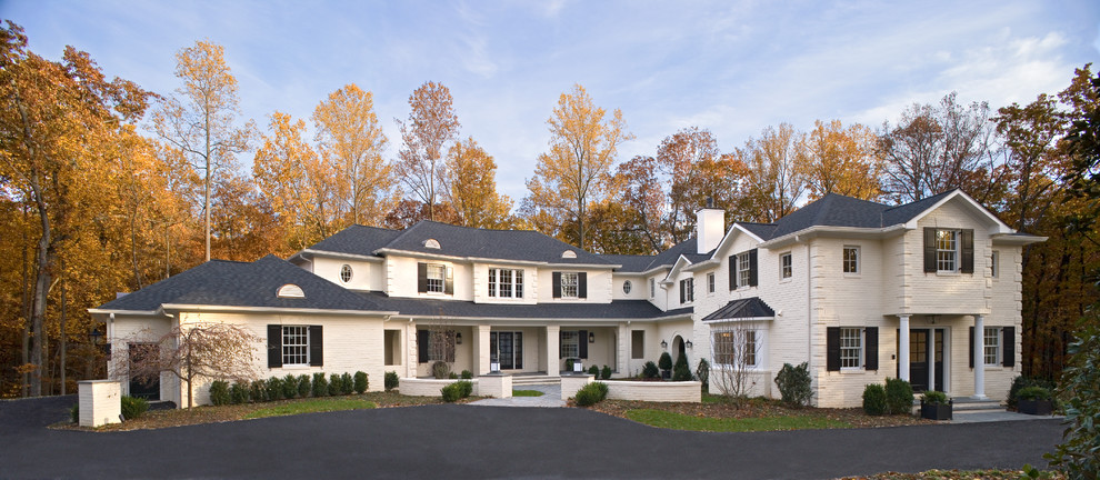 Immagine della villa bianca classica a due piani con rivestimento in mattoni, tetto a padiglione e copertura a scandole