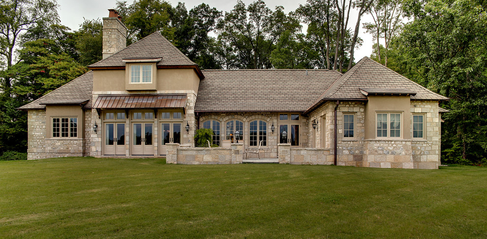 Foto de fachada de casa beige tradicional extra grande de dos plantas con revestimiento de piedra, tejado a cuatro aguas y tejado de teja de madera