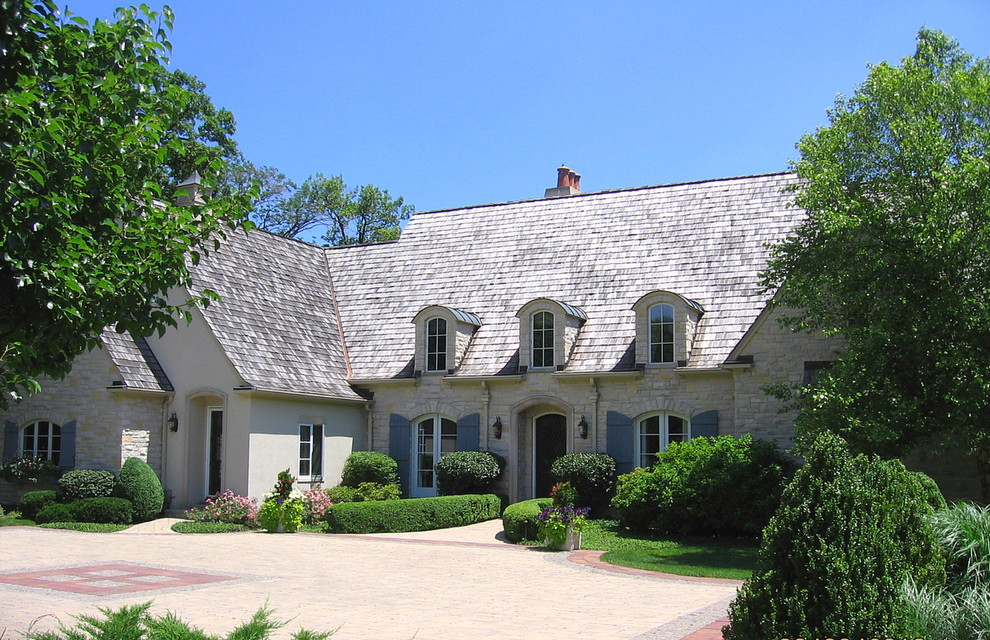 Immagine della facciata di una casa classica con rivestimento in pietra e copertura a scandole