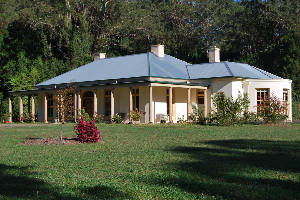 Diseño de fachada beige tradicional grande de una planta con revestimiento de estuco y tejado a cuatro aguas