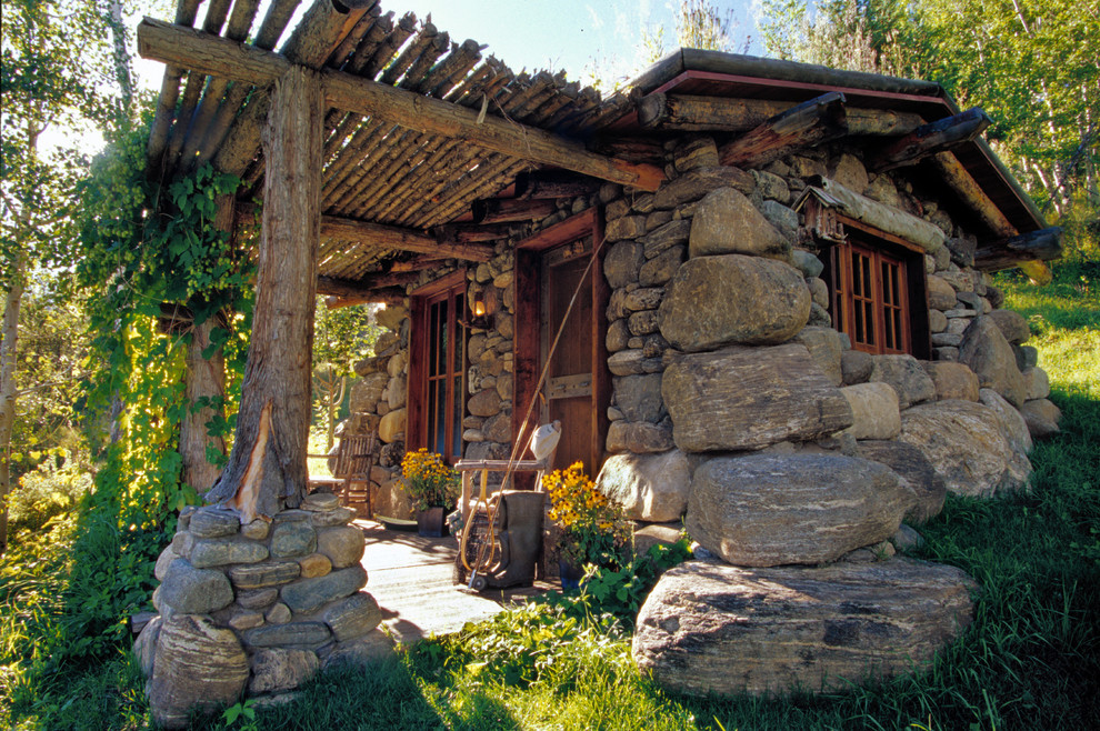 Пример оригинального дизайна: маленький дом в стиле рустика с облицовкой из камня для на участке и в саду