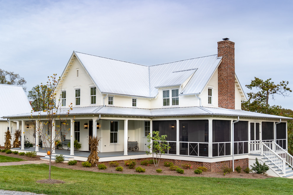 Esempio della villa grande bianca country a tre piani con rivestimento con lastre in cemento, copertura in metallo o lamiera e tetto a capanna