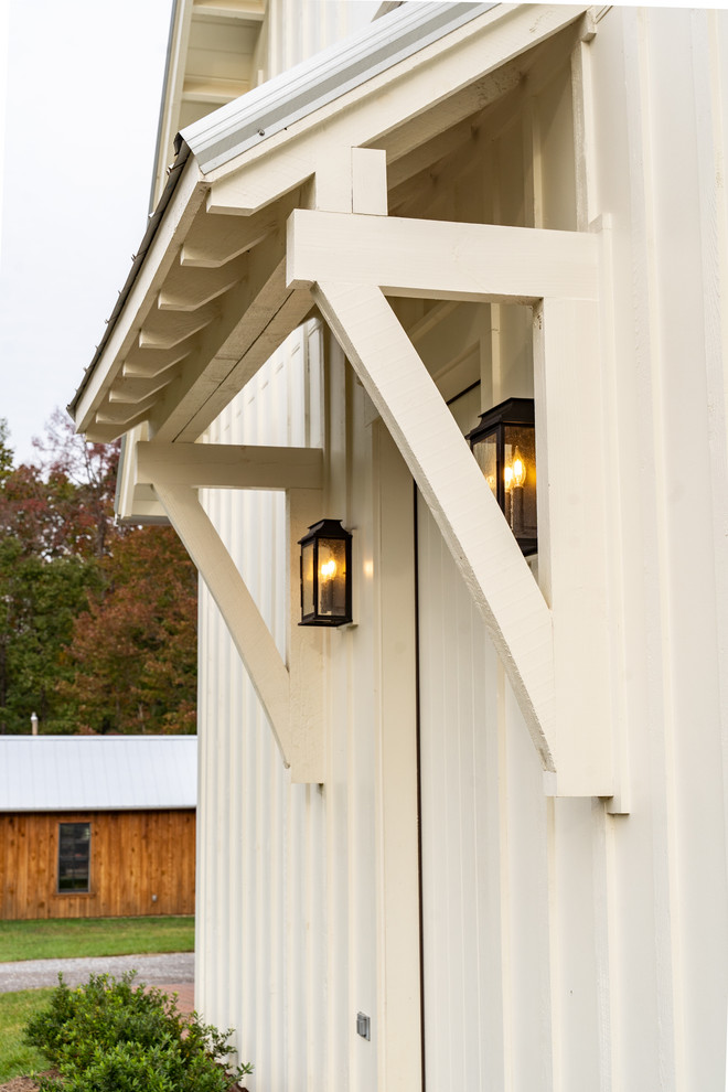 Immagine della villa grande bianca country a tre piani con rivestimento con lastre in cemento, copertura in metallo o lamiera e tetto a capanna