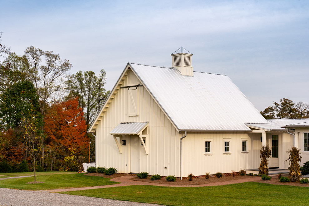 Foto på ett stort lantligt vitt hus, med tre eller fler plan, fiberplattor i betong, sadeltak och tak i metall