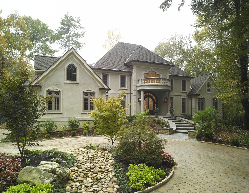 Large traditional gray two-story stucco exterior home idea in Atlanta with a hip roof