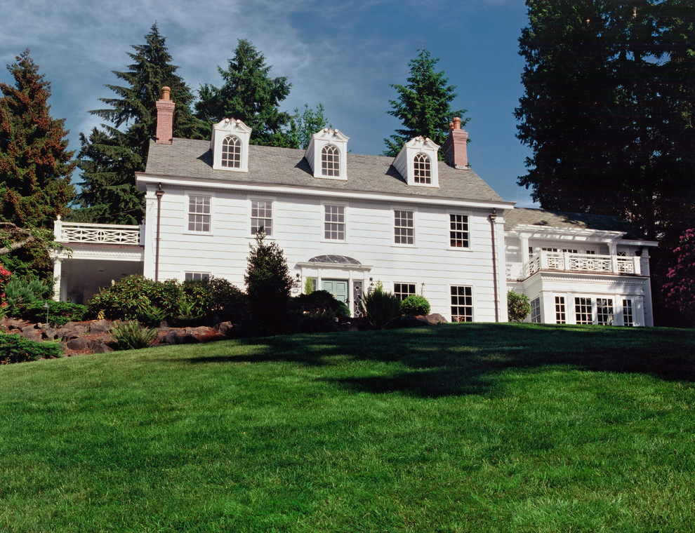 Imagen de fachada blanca clásica grande de tres plantas con revestimiento de madera y tejado a dos aguas
