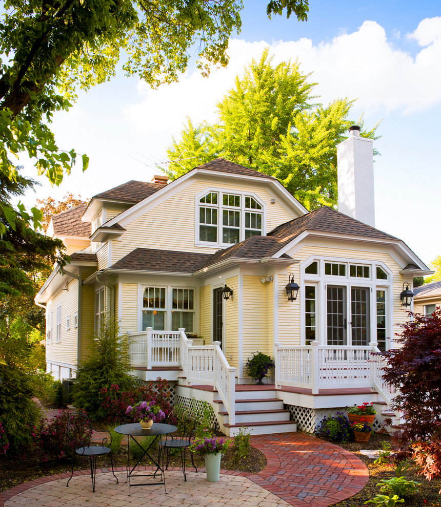 Inspiration for a timeless yellow two-story exterior home remodel in Chicago with a clipped gable roof
