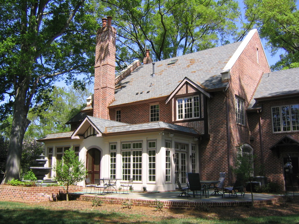 Esempio della facciata di una casa rossa classica a due piani con rivestimento in mattoni e tetto a capanna