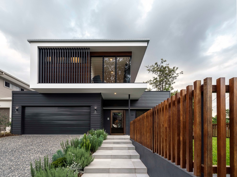 Modelo de fachada de casa negra contemporánea de dos plantas con revestimientos combinados y tejado plano