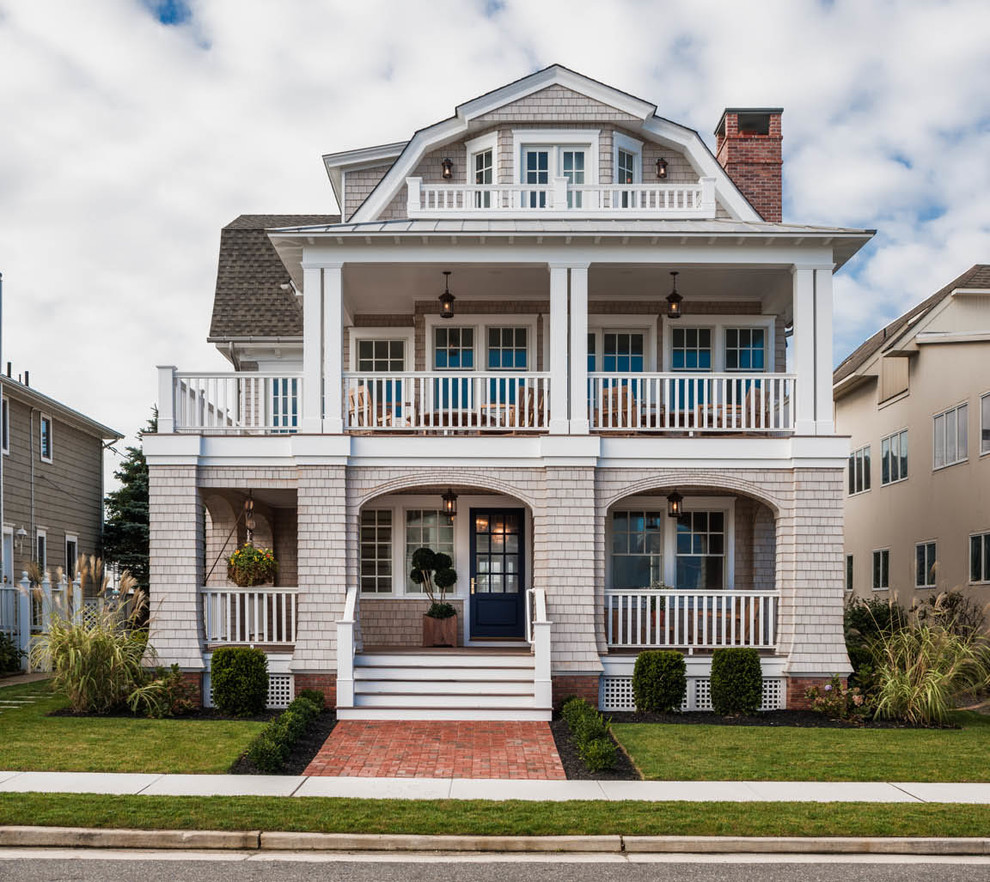 This is an example of a large and beige nautical house exterior in Philadelphia with three floors, wood cladding and a mansard roof.