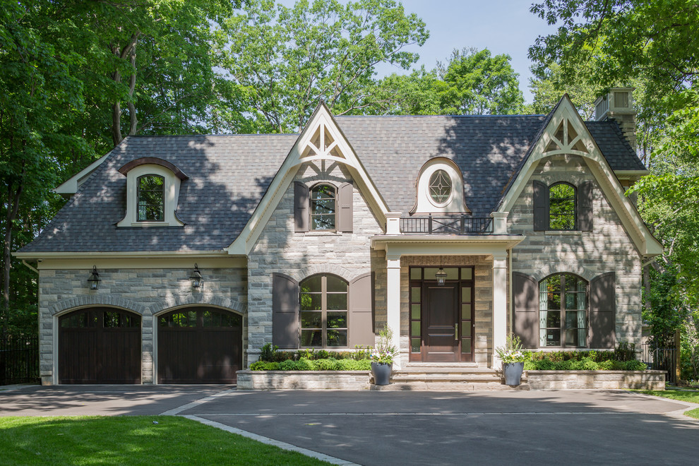 Пример оригинального дизайна: большой, двухэтажный дом в классическом стиле с облицовкой из камня и двускатной крышей