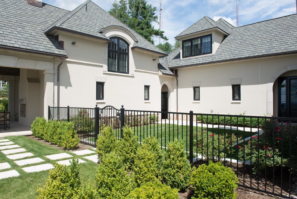 Esempio della villa ampia beige classica a tre piani con rivestimento in stucco, falda a timpano e copertura verde