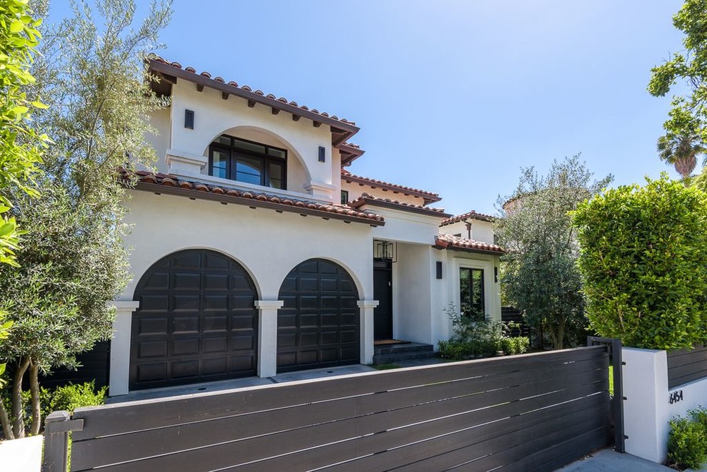 Large transitional beige two-story concrete house exterior photo in Los Angeles with a hip roof and a tile roof