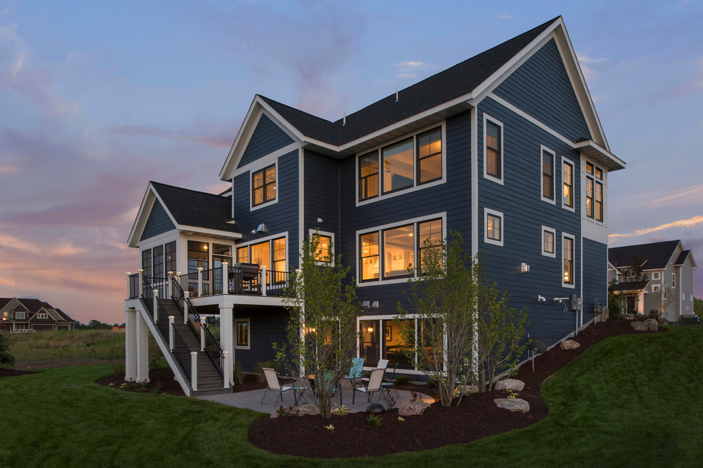 Cette photo montre une grande façade de maison bleue chic en panneau de béton fibré à un étage avec un toit à deux pans et un toit mixte.