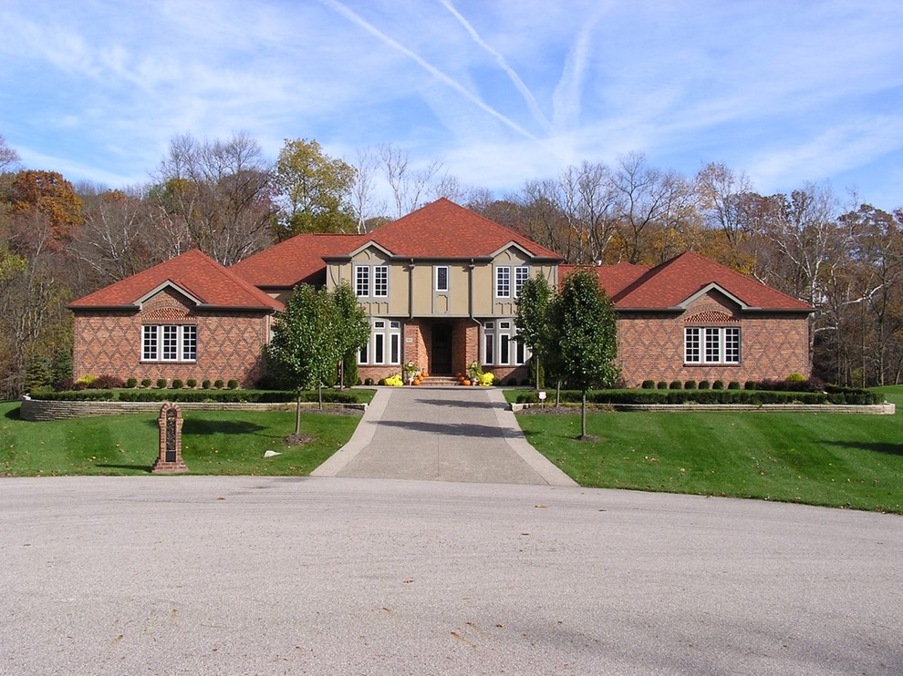 Large and red classic brick detached house in Columbus with three floors, a hip roof and a shingle roof.