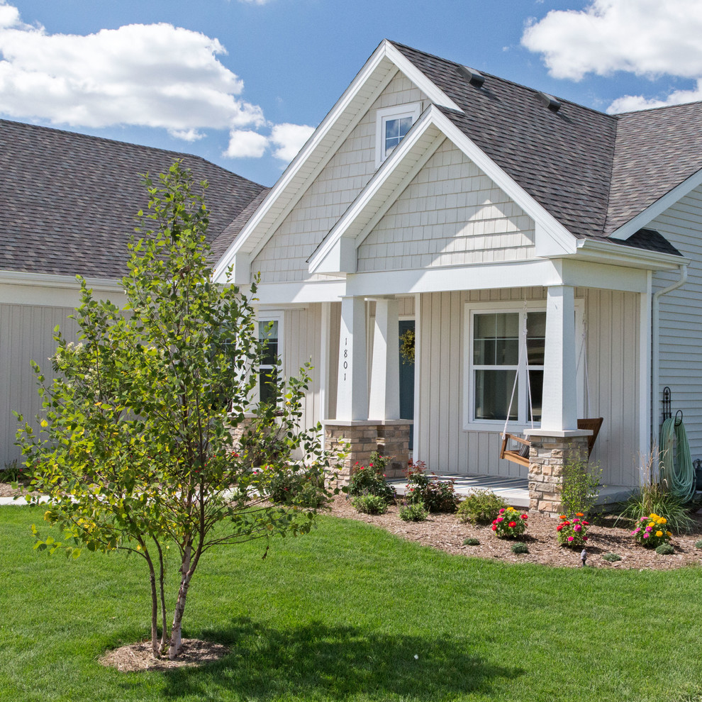 Modelo de fachada beige de estilo de casa de campo de tamaño medio de una planta con revestimiento de vinilo y tejado a dos aguas