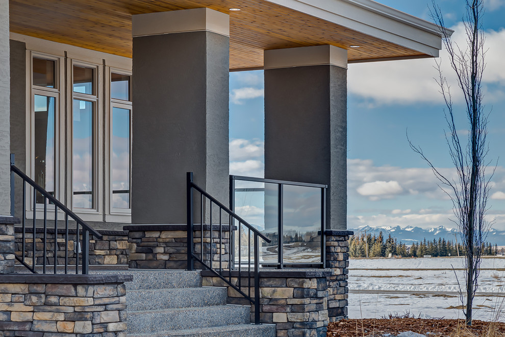 Mid-sized transitional gray two-story stucco exterior home photo in Calgary with a hip roof