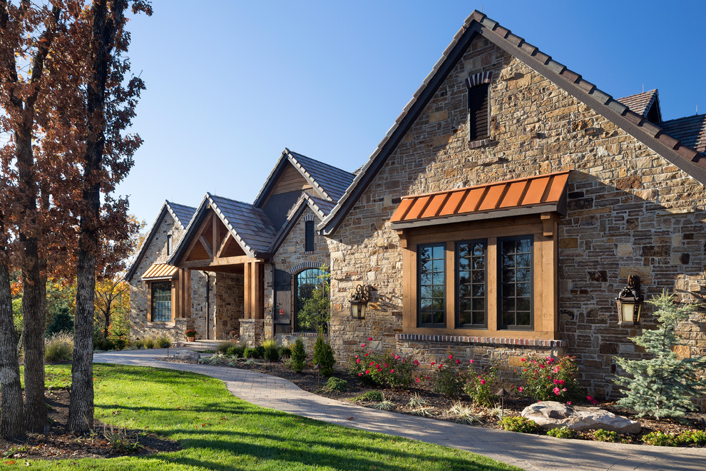 Стильный дизайн: большой, коричневый дом в стиле рустика с разными уровнями, облицовкой из камня и двускатной крышей - последний тренд
